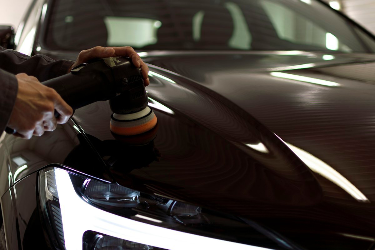Close-up of a polishing pad correcting paint on a black car hood